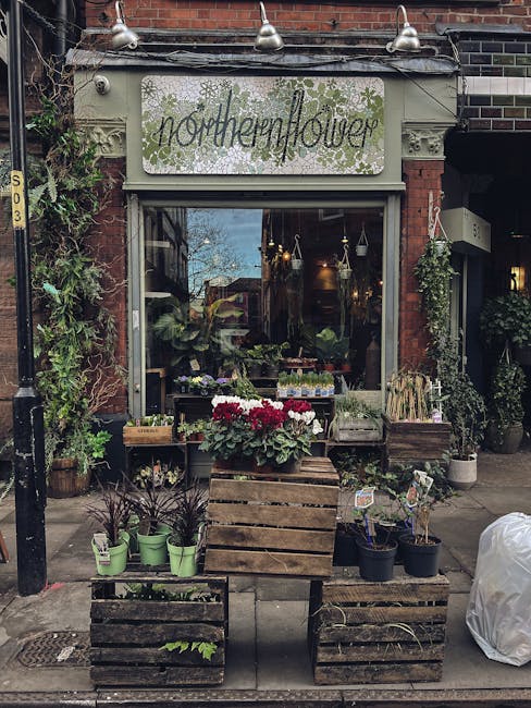 The exterior of Northenflower, a florist shop on Stoke Newington Church Street, featuring a large window display with potted plants and flowers arranged on wooden crates outside. The display includes